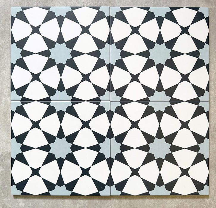 Agadir Blau Fliesen im marokkanischen Stil im Format 20 × 20 cm aus Feinsteinzeug, als Vierer-Anordnung dargestellt, um das sich wiederholende geometrische Sternmuster in Blau, Schwarz und Weiß auf neutralem Hintergrund zu zeigen.