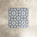 Fez Mini Artisan 15x15cm Moroccan-style porcelain tile displayed against a textured grey background, highlighting the intricate multicolour geometric star pattern in soft blue, blush pink, green and terracotta tones with an encaustic-inspired finish.