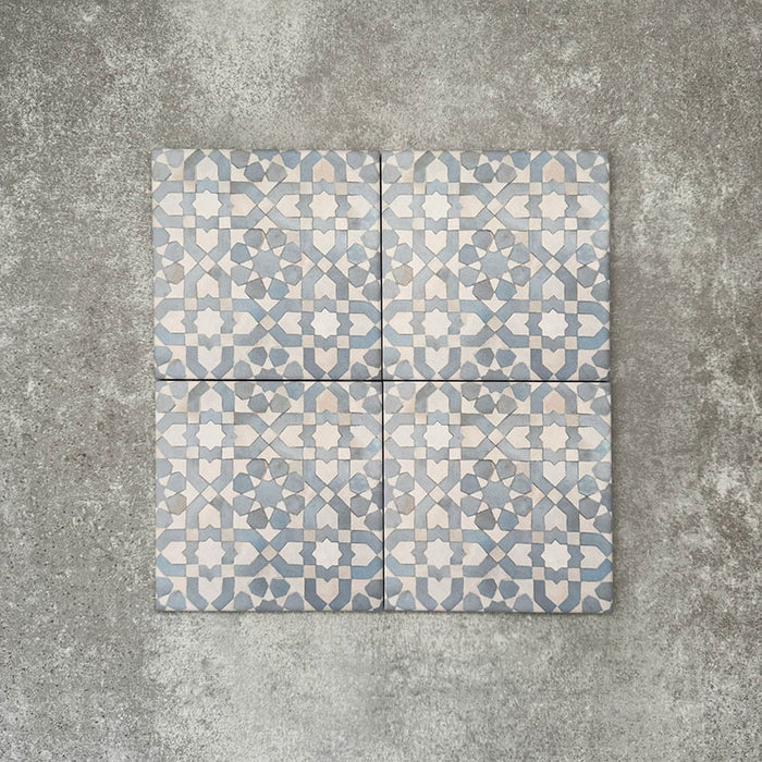 Vier Berber Tetuan Blau Feinsteinzeugfliesen im marokkanischen Stil im Format 15 × 15 cm, gemeinsam angeordnet, um das sanfte geometrische Muster in Blau und Creme auf neutralem Hintergrund hervorzuheben.