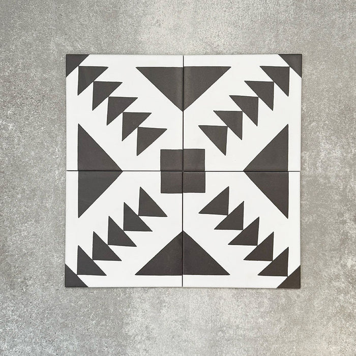 Almeira Azteca Feinsteinzeug-Bodenfliesen im marokkanischen Stil, dargestellt in einer Vierer-Anordnung, die das markante geometrische Muster in Schwarz und Weiß mit gestuften Dreiecken und zentralen Details zeigt, Format 20 × 20 cm.