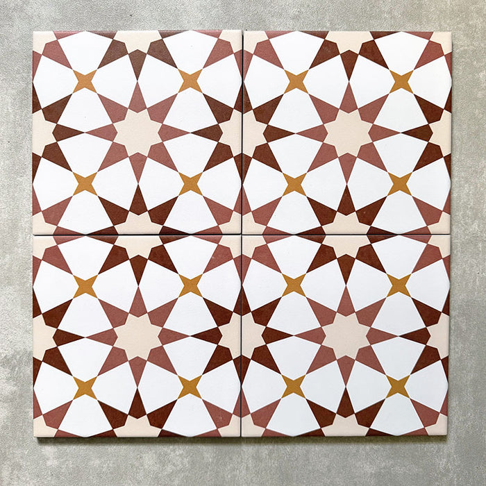 Agadir Terrakotta Fliesen im marokkanischen Stil im Format 20 × 20 cm aus Feinsteinzeug, als Vierer-Anordnung dargestellt, um das sich wiederholende geometrische Sternmuster in warmen Terrakotta-, Weiß- und sanften Gelbtönen auf neutralem Hintergrund zu zeigen.