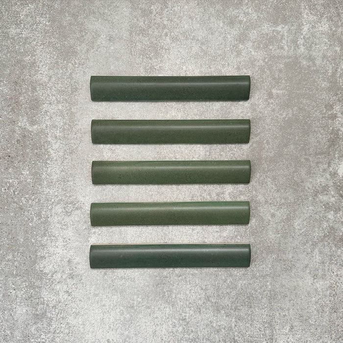 Flatlay mit Zellige Malachitgrün Matt Bullnose-Keramikfliesen im marokkanischen Stil im Format 3 × 20 cm, die das abgerundete Kantenprofil, die satte grüne Glasur und die feine tonale Variation vor neutralem Hintergrund zeigen.