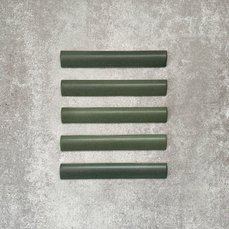 Flatlay mit Zellige Malachitgrün Matt Bullnose-Keramikfliesen im marokkanischen Stil im Format 3 × 20 cm, die das abgerundete Kantenprofil, die satte grüne Glasur und die feine tonale Variation vor neutralem Hintergrund zeigen.