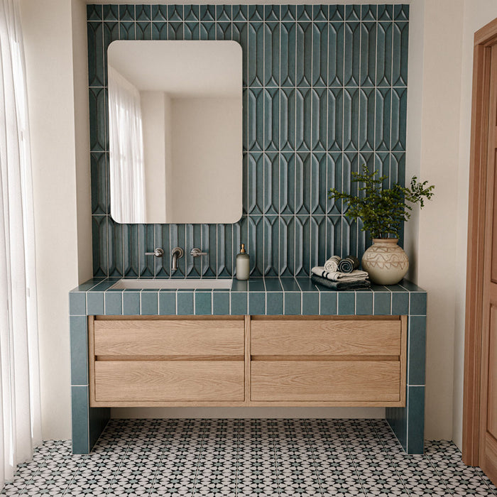Badezimmer mit Agadir Blau Bodenfliesen im Format 20 × 20 cm im marokkanischen Stil, mit einem schwarz-weißen geometrischen Muster, kombiniert mit blauen Wandfliesen, einem Waschtischunterschrank aus Holz und neutralen Deko-Elementen.