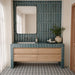 Badezimmer mit Agadir Blau Bodenfliesen im Format 20 × 20 cm im marokkanischen Stil, mit einem schwarz-weißen geometrischen Muster, kombiniert mit blauen Wandfliesen, einem Waschtischunterschrank aus Holz und neutralen Deko-Elementen.