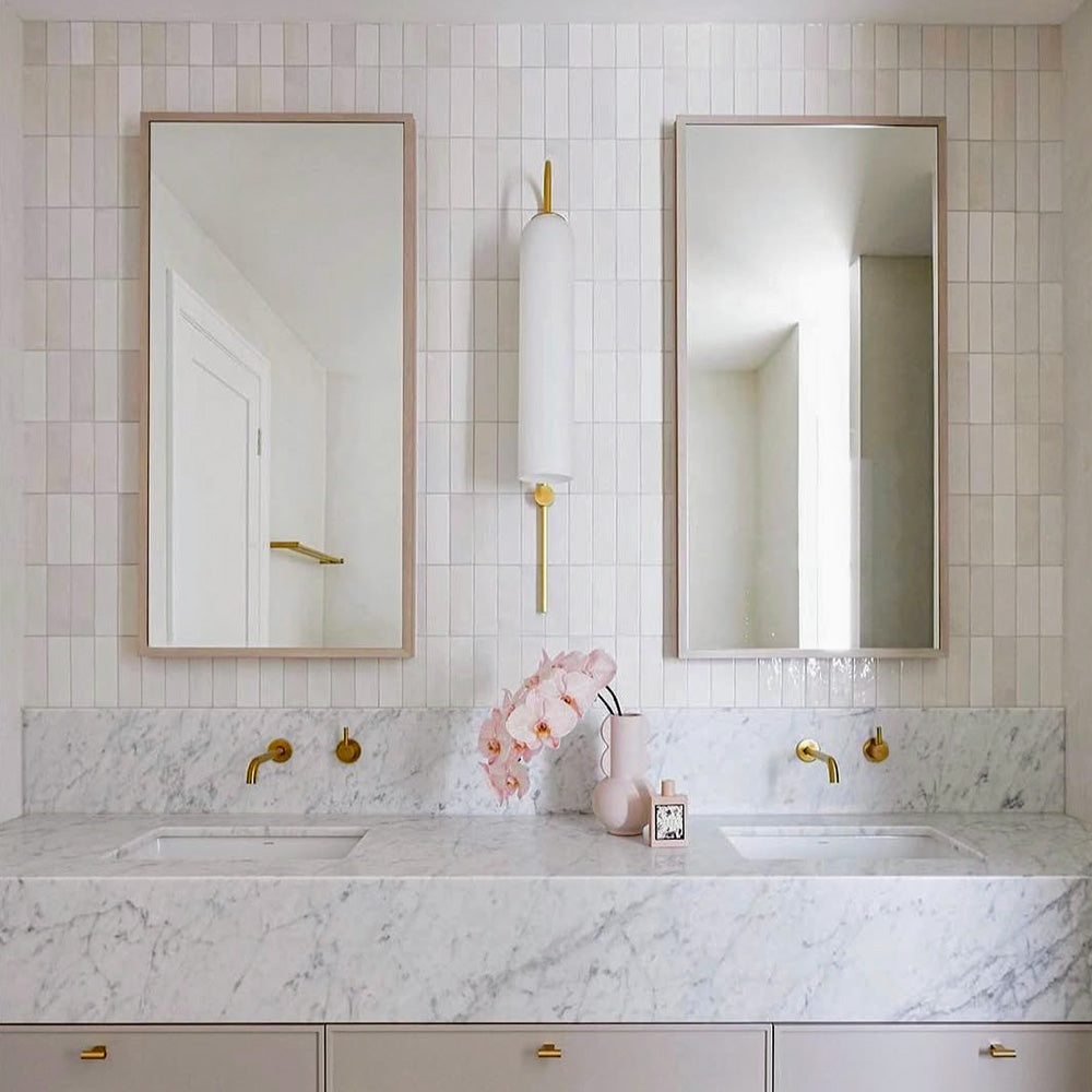 Badezimmer mit Atlas White Mini Brick Gloss glänzenden Wandfliesen im Format 5 × 15 cm, kombiniert mit Marmoroberflächen, Armaturen in Messingoptik und sanften neutralen Farbtönen für ein elegantes, modernes Badezimmerdesign.