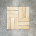 Flatlay von Zellige Sandbeige Matt Ziegel Keramikfliesen im marokkanischen Stil im Format 6,5 × 20 cm, in warmen Beige- und Cremetönen. Im Flechtmuster (Basketweave) auf strukturiertem grauem Hintergrund angeordnet, mit subtiler Farbvariation und leicht unregelmäßigen Kanten zur Betonung der handgefertigten Zellige-Optik.