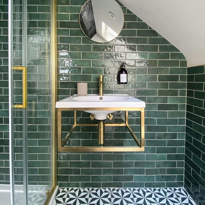 Badezimmer mit Zellige Königliches Grün Ziegel Keramik-Wandfliesen im marokkanischen Stil im Format 6,5 × 20 cm, horizontal im Ziegelverband rund um ein wandhängendes Waschbecken verlegt. Kombiniert mit Messingarmaturen, Glasduschabtrennung und gemusterten Bodenfliesen entsteht ein mutiges, elegantes Finish mit Zellige-Effekt.