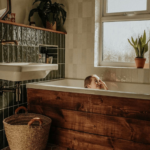 Badezimmer mit Zellige Botanisches Grün Ziegel Keramik-Wandfliesen im marokkanischen Stil im Format 6,5 × 20 cm, in tiefen Grüntönen. Vertikal im Ziegelverband rund um eine eingebaute Badewanne verlegt und kombiniert mit warmer Holzverkleidung, weißer Keramik und botanischen Akzenten entsteht ein reiches, charaktervolles Finish mit Zellige-Effekt.