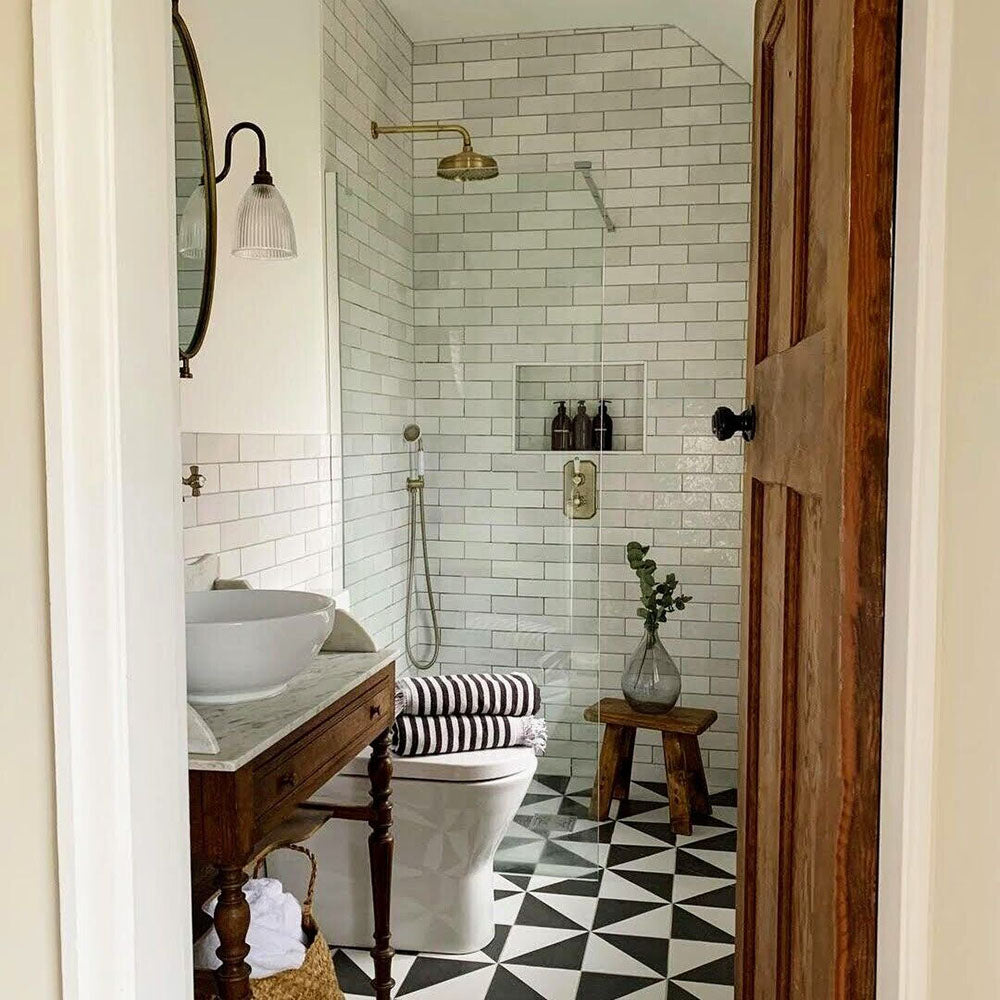 Badezimmer mit Zellige Weiß Ziegel Fliesen, horizontal an den Wänden verlegt und kombiniert mit gemusterten Bodenfliesen sowie Armaturen in Messing.