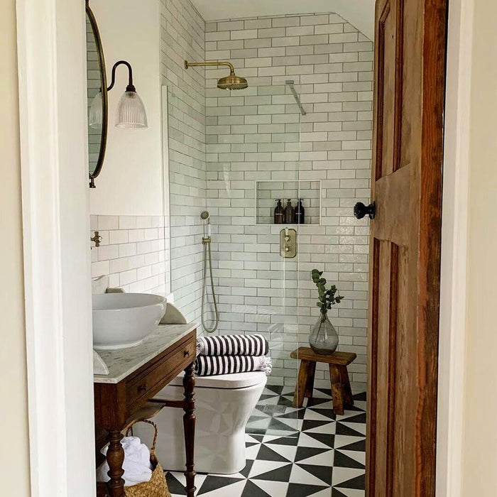 Badezimmer mit Zellige Weiß Ziegel Fliesen, horizontal an den Wänden verlegt und kombiniert mit gemusterten Bodenfliesen sowie Armaturen in Messing.