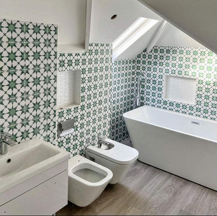 Badezimmerinterieur mit Agadir Grün Fliesen im marokkanischen Stil im Format 20 × 20 cm aus Feinsteinzeug, eingesetzt als Wandfliesen mit sich wiederholendem geometrischem Sternmuster in Grün und Weiß. Kombiniert mit freistehender Badewanne, moderner Sanitärausstattung und einer hellen, luftigen Raumgestaltung.