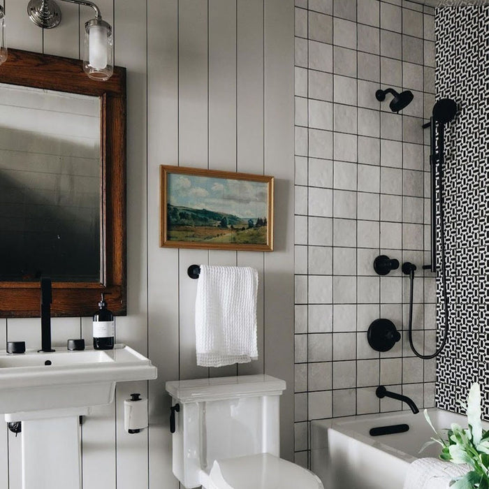 Badezimmer mit Zellige Weiß Quadrat Fliesen in sauberer Rasterverlegung, kombiniert mit schwarzen Armaturen und klassischen Details für eine zeitlose, moderne Ausstrahlung.