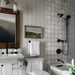 Badezimmer mit Zellige Weiß Quadrat Fliesen in sauberer Rasterverlegung, kombiniert mit schwarzen Armaturen und klassischen Details für eine zeitlose, moderne Ausstrahlung.