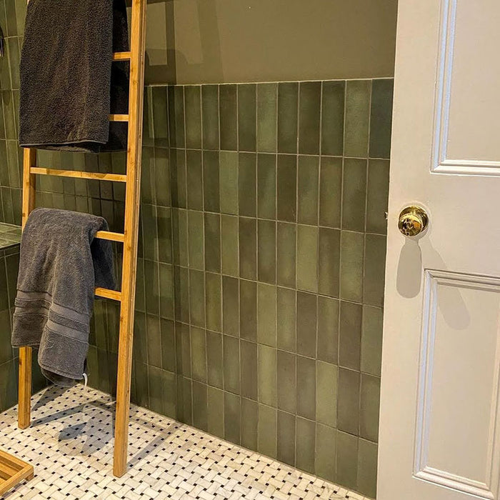 Badezimmer mit Zellige Malachitgrün Matt Keramik-Riemchenfliesen im marokkanischen Stil im Format 6,5 × 20 cm, rund um Badewanne und Dusche an den Wänden installiert. Die Kombination aus Messing, Holz und Stein sorgt für ein entspanntes, hochwertiges Finish.