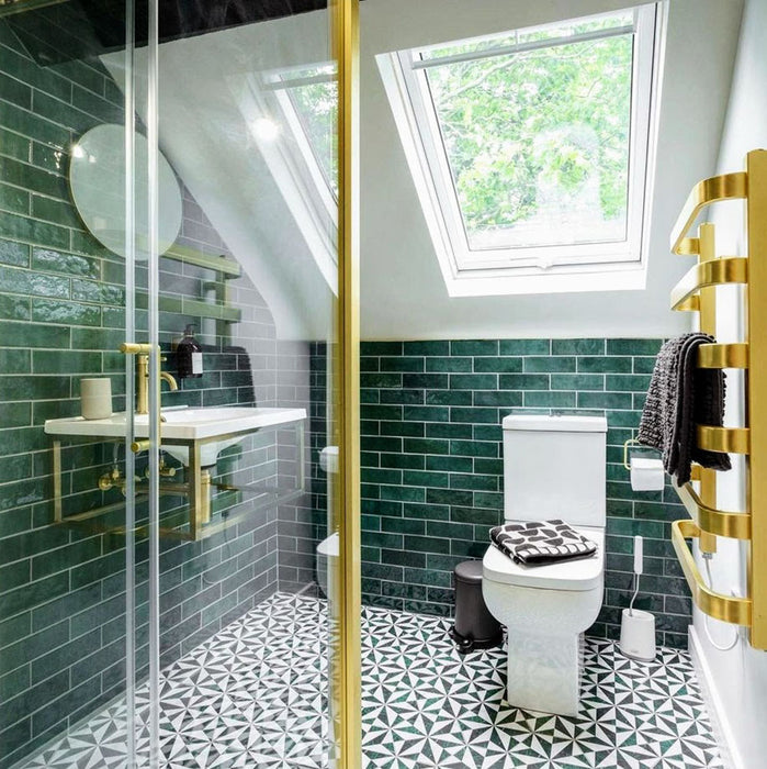 Badezimmer mit Zellige Königliches Grün Ziegel Keramik-Wandfliesen im marokkanischen Stil im Format 6,5 × 20 cm, horizontal im Ziegelverband rund um ein wandhängendes Waschbecken verlegt. Messingarmaturen, Glasduschabtrennung und gemusterte Bodenfliesen sorgen für ein kraftvolles, elegantes Gesamtbild.