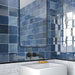 Badezimmer mit Zellige Königliches Blau Keramik-Quadratfliesen im marokkanischen Stil im Format 13,2 × 13,2 cm, an den Wänden verlegt. Die satten Blautöne mit glänzender Glasur in handgefertigter Optik werden kombiniert mit mattschwarzen Armaturen, einem minimalistischen Waschtisch und einem modernen Spiegel.