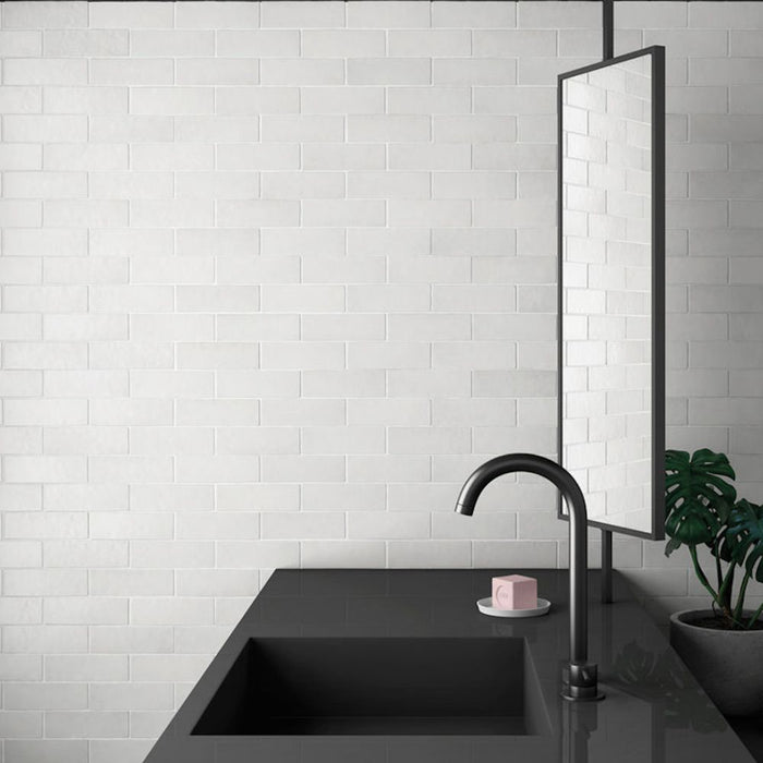 Badezimmerwand mit Zellige Kreideweiß Matt Riemchenfliesen im marokkanischen Stil im Format 6,5 × 20 cm, kombiniert mit einem mattschwarzen Waschbecken und Spiegel.