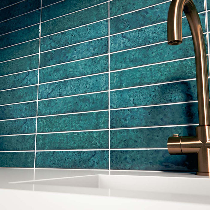 Küchenrückwand mit Bora Bora Brick Amun Blue Wandfliesen im Format 6,5 × 32,8 cm, die die satten blau schimmernden Flux-Glasureffekte zur Geltung bringen. Kombiniert mit einer weißen Arbeitsplatte, einem integrierten Spülbecken und einer Armatur in gebürsteter Messingoptik entsteht ein eleganter und zeitgemäßer Look.