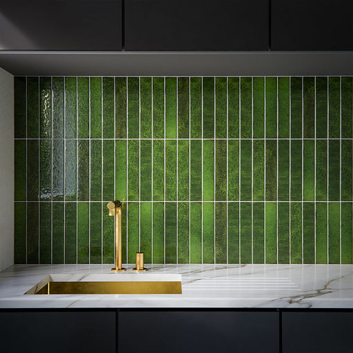 Moderne Küchenrückwand mit Bora Bora Brick Tourmaline Green Wandfliesen im Format 6,5 × 32,8 cm, kombiniert mit dunklen Küchenfronten, einer Arbeitsplatte in Marmoroptik und Armaturen in gebürsteter Messingoptik für eine luxuriöse Ausstrahlung.