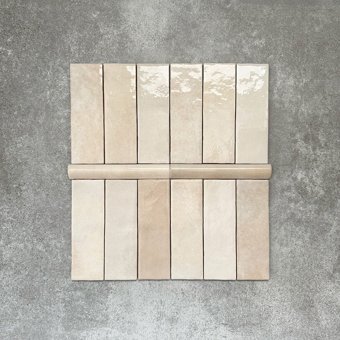 Zellige Beige Bullnose-Keramikfliesen in sanftem Beigeton, kombiniert mit passenden Riemchenfliesen, als Flatlay ausgelegt.