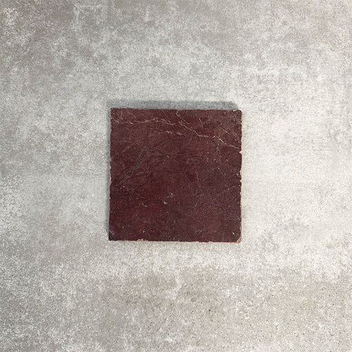 Einzelne Fayrouz Bordeaux 15,2 × 15,2 cm Naturmarmorfliese mit getrommelter Oberfläche in tiefen Rottönen mit natürlicher Maserung, präsentiert vor einem neutralen, strukturierten Hintergrund in einer klaren Produktszene.