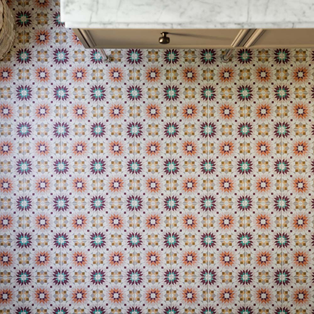 Boden mit Kuba Manzanillo Musterfliesen im Format 20 × 20 cm im marokkanischen Stil, mit einem detailreichen geometrischen Design in Rosa, Grün, Burgunderrot und warmen neutralen Tönen, das unter klassischen Schränken einen farbenfrohen Blickfang schafft.