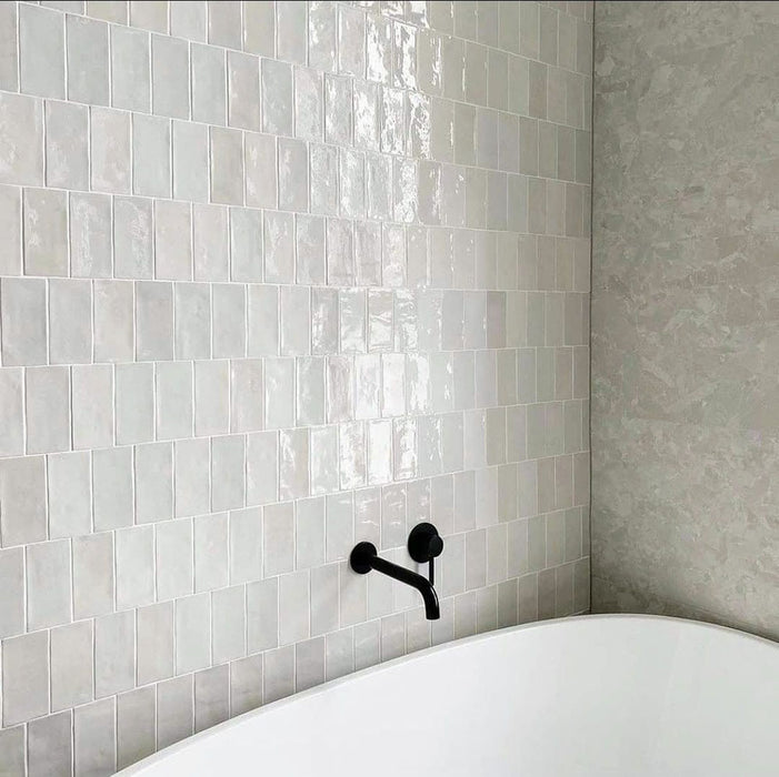 Badezimmerwand mit Zellige Auster Quadrat Fliesen im marokkanischen Stil im Format 10 × 10 cm, mit sanft glänzender Oberfläche, im schlichten Raster verlegt, für einen hellen, strukturierten Hintergrund mit dezenter tonaler Variation.