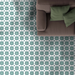 Wohnzimmer mit Agadir Grün Fliesen im marokkanischen Stil im Format 20 × 20 cm aus Keramik, verlegt als Bodenbelag mit markantem geometrischem Muster. Kombiniert mit einem neutralen Sofa, grünen Kissen und sanfter, zeitgemäßer Dekoration für eine frische, ausgewogene Raumwirkung.