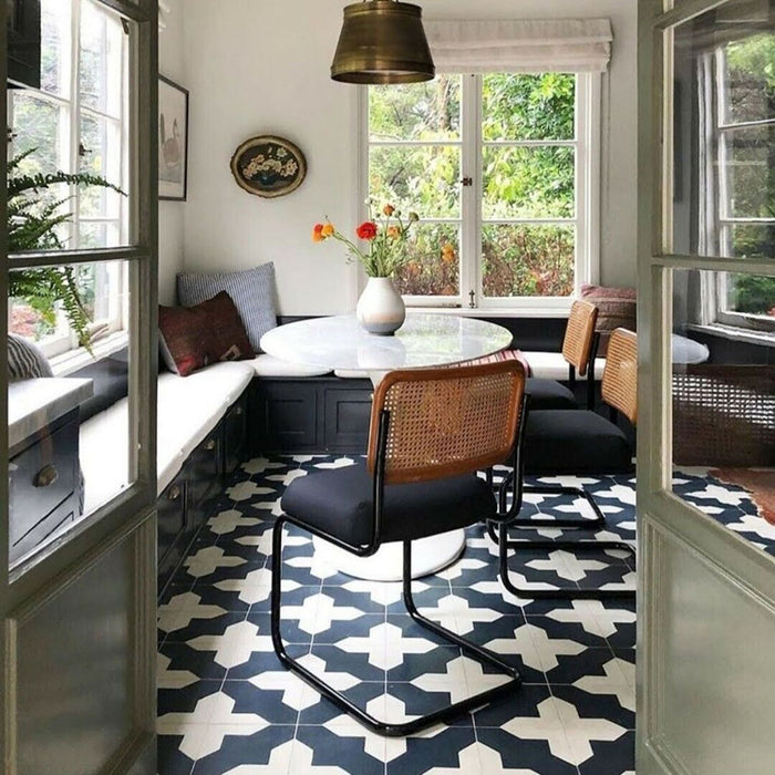 Badezimmer mit Almeria Kathedrale Feinsteinzeugfliesen im marokkanischen Stil im Format 20 × 20 cm als Bodenbelag. Das markante geometrische Muster in Schwarz und Weiß wird durch helle Holzwaschtische und weiße Wandfliesen ergänzt.