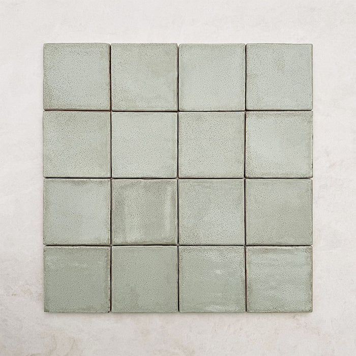 Quadratische Verlegung mit Dordogne Matcha Green Rustic Gloss Wandfliesen im Format 10 × 10 cm in sanften Grüntönen mit dezenten Farbvariationen und rustikaler Glanzoberfläche, die den handwerklich inspirierten Charakter und die leicht strukturierte Oberfläche der Kollektion hervorheben.