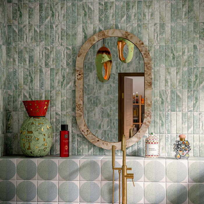 Badezimmer mit Eclipse Salvia Wand- und Bodenfliesen im Terrazzo-Look im Format 20 × 20 cm, kombiniert mit einer freistehenden Badewanne in Steinoptik, grünen Brick-Fliesen in Marmoroptik, Armaturen in gebürsteter Messingoptik und modernem, von der Natur inspiriertem Interior-Design.