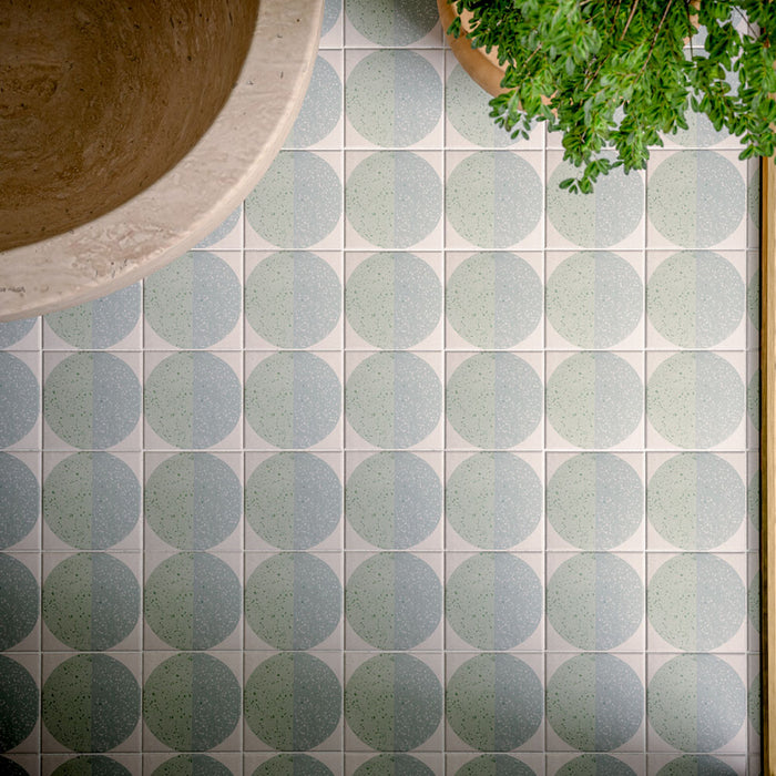 Badezimmer mit Eclipse Salvia Wand- und Bodenfliesen im Terrazzo-Look im Format 20 × 20 cm, kombiniert mit einer freistehenden Badewanne in Steinoptik, grünen Brick-Fliesen in Marmoroptik, Armaturen in gebürsteter Messingoptik und modernem, von der Natur inspiriertem Interior-Design.