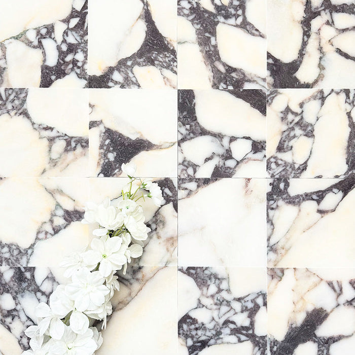 Fayrouz Calacatta Viola honed natural marble tile in a 15.2cm x 15.2cm square format, featuring a creamy white background with bold purple veining and subtle warm gold tones, creating a luxurious and timeless natural stone finish.