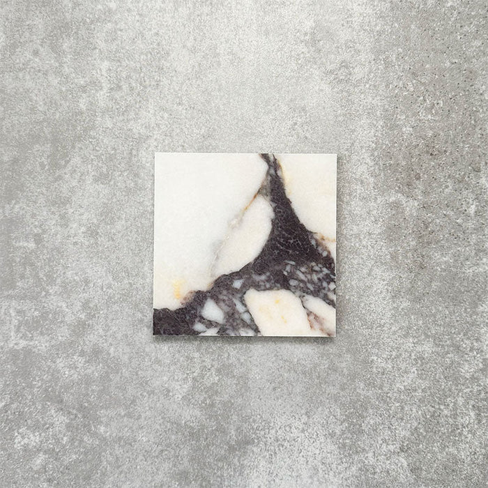 Fayrouz Calacatta Viola honed natural marble tile in a 15.2cm x 15.2cm square format, featuring a creamy white background with bold purple veining and subtle warm gold tones, creating a luxurious and timeless natural stone finish.