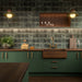 Kitchen featuring Fayrouz Verde Tumbled Finish Natural Marble 15.2cm x 15.2cm splashback tiles, paired with deep green cabinetry, dark wooden worktops, brass fittings, open shelving and warm ambient lighting for a timeless design.