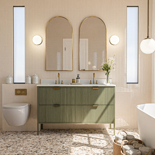 Badezimmer mit vertikal verlegten Gallery Beige Glänzenden Wandfliesen im Format 5 × 20 cm in einem sanften neutralen Farbton, kombiniert mit Bodenfliesen im Terrazzo-Stil, einem geriffelten grünen Waschtischunterschrank, Messingdetails und Rundbogenspiegeln.