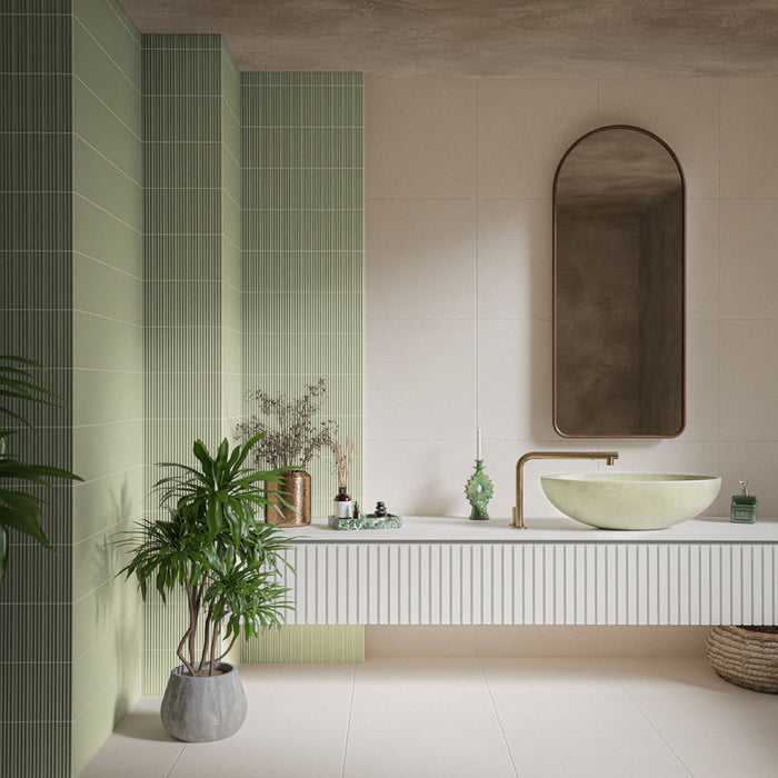 Badezimmer mit Gallery Rainfarn Grün Matt DEKOR Wandfliesen im Format 5 × 20 cm, kombiniert mit großformatigen neutralen Fliesen, einem schwebenden Waschtischunterschrank, einem Aufsatzwaschbecken, einem Rundbogenspiegel und grünen Pflanzen.