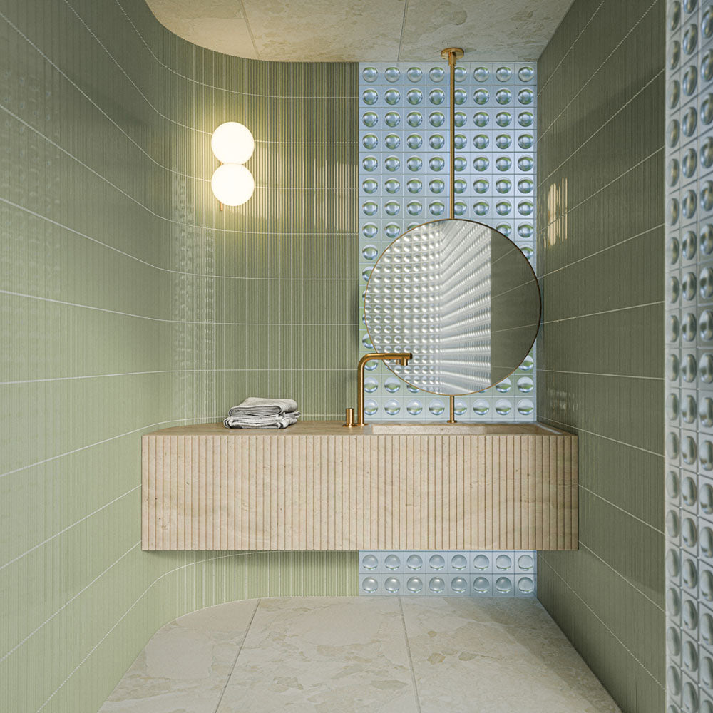 Badezimmer mit Gallery Rainfarn Grün DEKOR Glänzenden Wandfliesen im Format 5 × 20 cm, kombiniert mit strukturierten Akzentfliesen, einem schwebenden Waschtisch in Steinoptik, einem runden Spiegel und Messingarmaturen.
