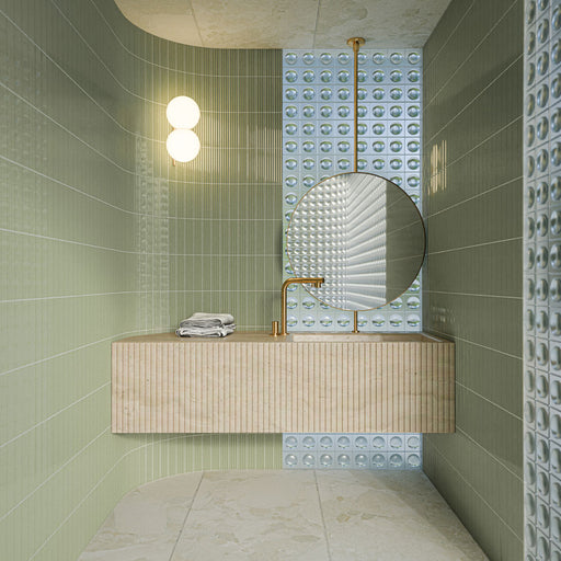 Badezimmer mit Gallery Rainfarn Grün DEKOR Glänzenden Wandfliesen im Format 5 × 20 cm, kombiniert mit strukturierten Akzentfliesen, einem schwebenden Waschtisch in Steinoptik, einem runden Spiegel und Messingarmaturen.
