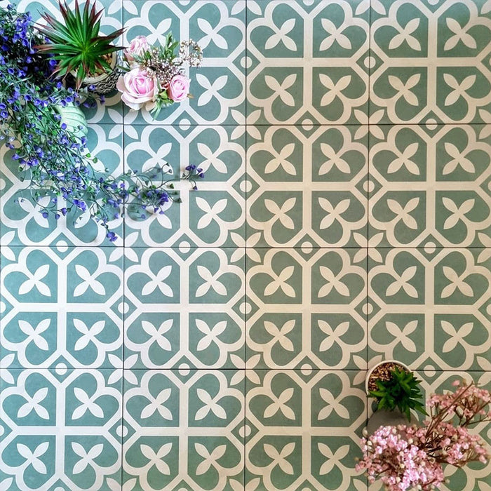 Kuba Ivy Grün Feinsteinzeugfliesen im viktorianisch-marokkanischen Stil im Format 20 × 20 cm, gezeigt in einer Flatlay-Darstellung mit dekorativen Pflanzen, um das geometrische Design hervorzuheben.
