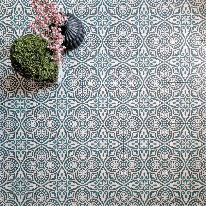 Kuba Fleur de Lis Feinsteinzeugfliesen im marokkanischen Stil im Format 20 × 20 cm, angeordnet in einem sich wiederholenden dekorativen Muster mit sanften Grün- und Weißdetails. Mit floralen Accessoires kombiniert, um die filigranen Motive und den klassischen Zementfliesen-Look zu betonen.