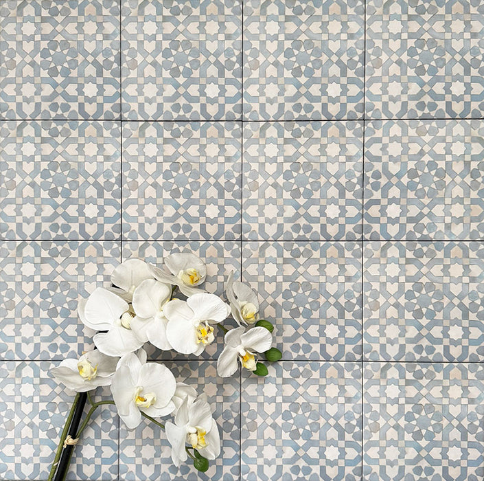 Berber Tetuan Blau Feinsteinzeugfliesen im marokkanischen Stil im Format 15 × 15 cm, verlegt im Raster, um das weiche geometrische Design in Blau und Creme zu präsentieren. Mit floraler Dekoration in Szene gesetzt für eine dekorative, wohnliche Wirkung.