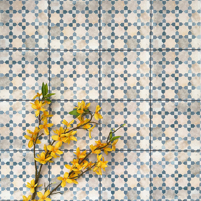 Berber Mequinez Blau Feinsteinzeugfliesen im marokkanischen Stil im Format 15 × 15 cm, verlegt im Raster, um das sanfte geometrische Design in Blau und Creme zu zeigen. Mit floraler Dekoration in Szene gesetzt für eine dekorative Optik.