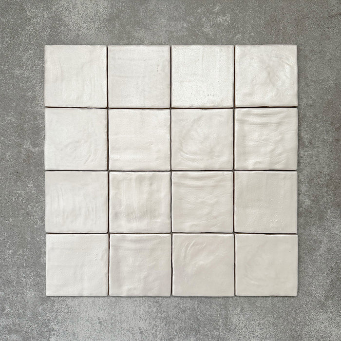 Flatlay mit Zellige Auster Quadrat Keramikfliesen im marokkanischen Stil im Format 10 × 10 cm, das die sanft unregelmäßigen Kanten, feine Oberflächenwellen und die dezente tonale Variation hervorhebt, die den handgefertigten Charakter der glänzenden Auster-Glasur unterstreichen.