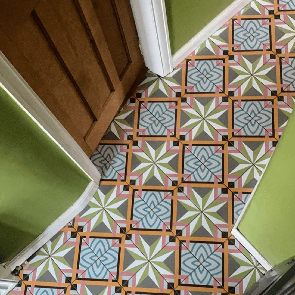 Flurboden mit Kuba Stern Feinsteinzeugfliesen im marokkanischen Stil im quadratischen Format 20 × 20 cm, verlegt in einem sich wiederholenden geometrischen Muster in sanften Grün-, Blau-, Rosa- und Senftönen. Kombiniert mit grünen Wänden und Holztüren entsteht ein lebendiger, charaktervoller Eingangsbereich.