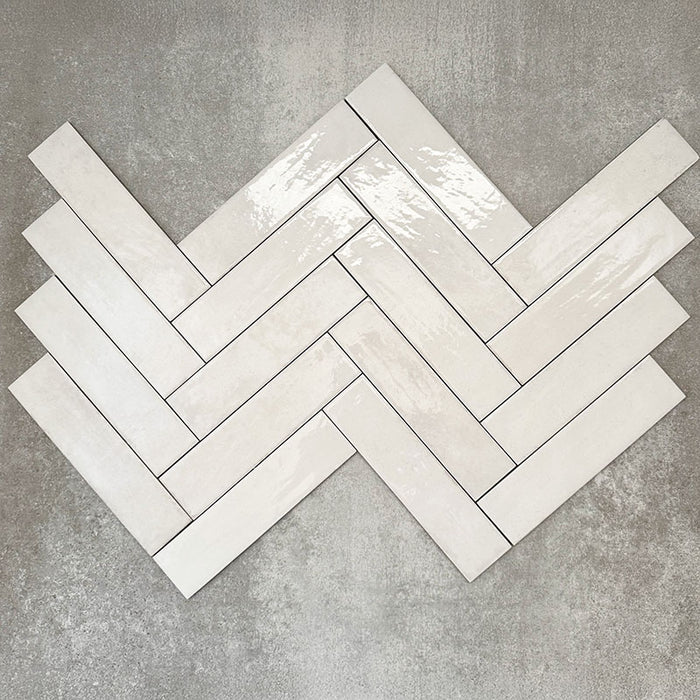 Nomadin Brick Weiß Wandfliesen im Format 6 × 24,6 cm, im Fischgrätmuster verlegt, um den sanften Weißton, die glänzende Oberfläche und die feine Oberflächenvariation hervorzuheben.