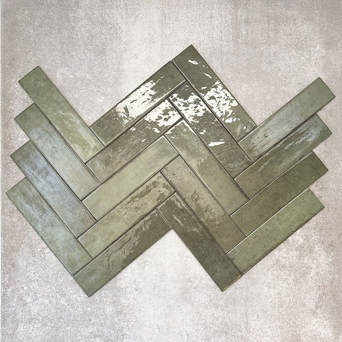 Nomadin Brick Salbeigrün Wandfliesen im Format 6 × 24,6 cm, im Fischgrätmuster verlegt, mit glänzender, leicht strukturierter Oberfläche und tiefen Grüntönen – ideal für Wandflächen im Industrial-Stil.