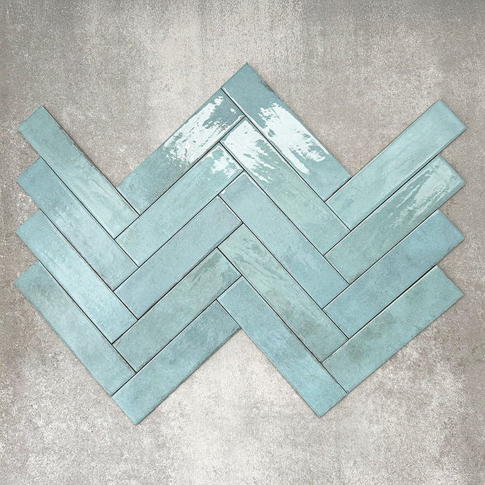 Nomadin Aqua Ziegel-Wandfliesen im Format 6 × 24,6 cm, im Fischgrätmuster verlegt, mit glänzender, leicht strukturierter Oberfläche und sanften Blau-Grün-Tönen – im Industrial-Stil.