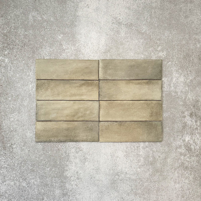 Flatlay von Zellige Waldgrün Matt Keramik-Riemchenfliesen im marokkanischen Stil im Format 6,5 × 20 cm, mit weicher grüner und erdiger Farbvariation, unregelmäßigen Kanten und handgefertigter Glasur vor neutralem Hintergrund.